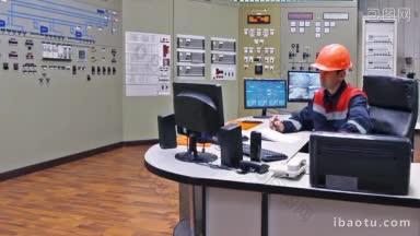 工程师坐在压缩气压站主控板上的桌子边接电话边说话
